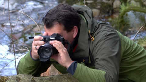 Ein Mann fotografiert Naturmotive an einem Fluss