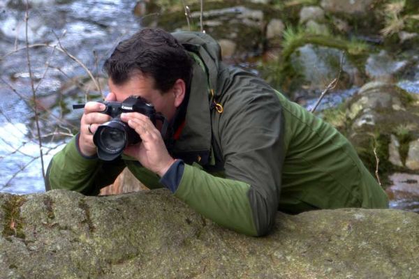 Ein Mann fotografiert Naturmotive an einem Fluss